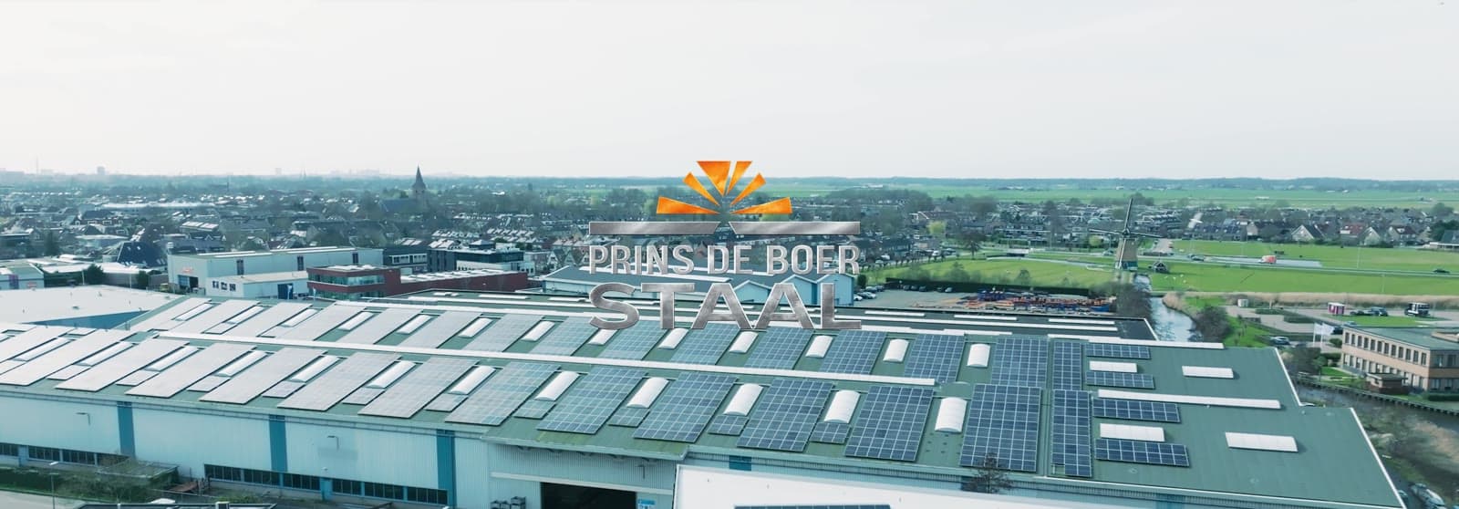 Luchtfoto van de hal van Prins de Boer Staal met het logo op het dak, still uit de brand film